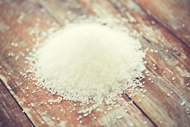 food, junk-food, cooking and unhealthy eating concept - close up of white sea salt heap on wooden table