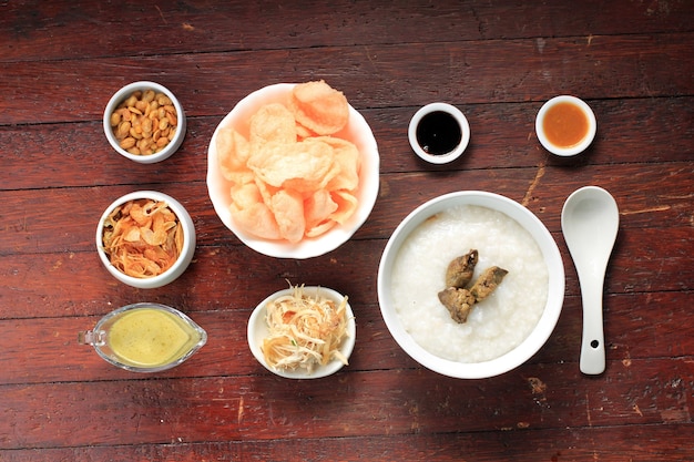 Food Knolling Concept Bubur Ayam of Indonesische rijstpap met geraspte kip. Geserveerd met Kerukpuk (Cracker), Sojasaus, Gebakken Sojaboon en Sambal