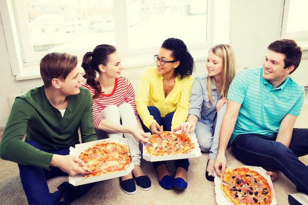 food, leisure and happiness concept - five smiling teenagers eating pizza at home