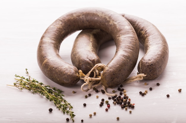 Cibo, carne e delizioso concetto - close up di salsiccia di carne di cavallo con cumino e pepe su bianco