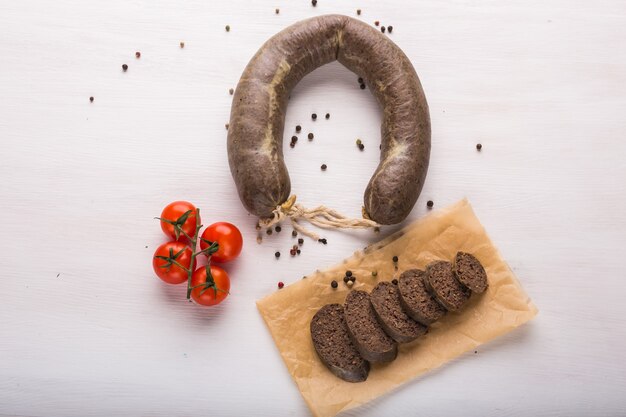 Food, meat and delicious concept - sausages made with horse meat with tomatoes on table.