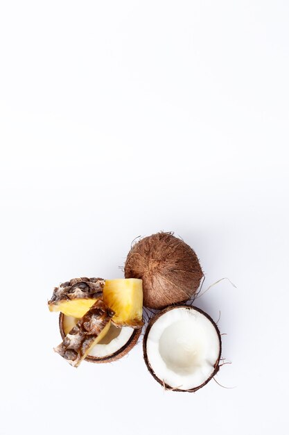 Food, minimalism, color, still life, minimalism and natural concept - pineapple and coconut on a white background