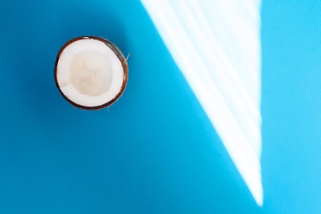 Cibo, minimalismo, colore, natura morta e concetto naturale - mezza noce di cocco isolata su sfondo blu. tracciato di ritaglio