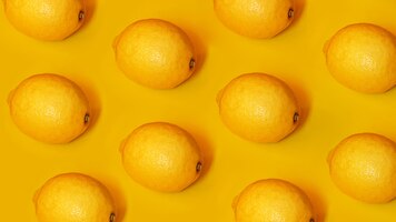 Фото Продовольственный образец с лимонами на желтой бумажной предпосылке. вид сверху. летняя концепция. веганская и вегетарианская диета.