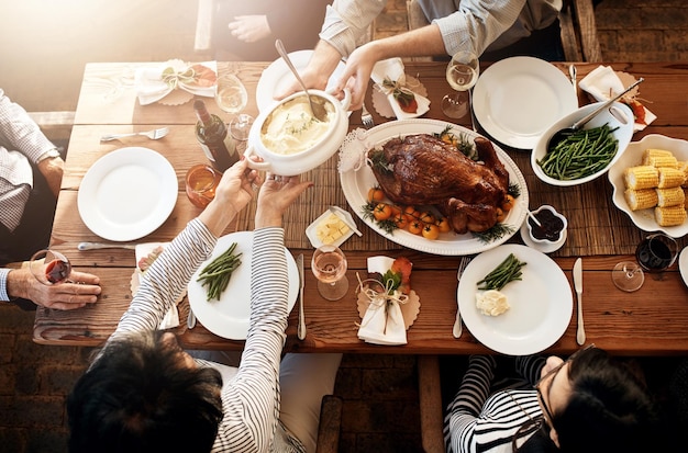 写真 食べ物を食べる人々と、休日のお祝いやディナーパーティーのためにテーブルで一緒に食事をする家族や友人のグループの上で、鶏肉や七面鳥の野菜とワインドリンクを使った健康的なランチを共有する手