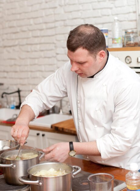 Food and people concept male chef with cooked food standing in the kitchen