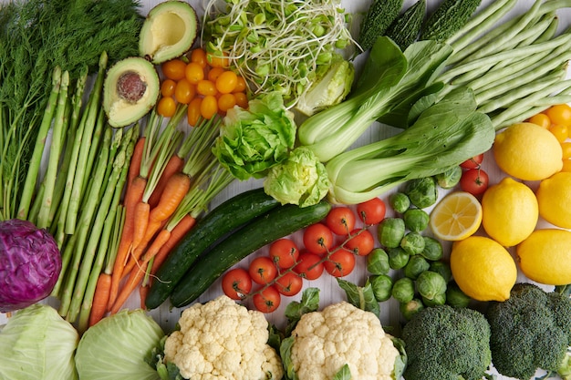 Продовольственная фотография различных фруктов и овощей на поверхности белого деревянного стола.