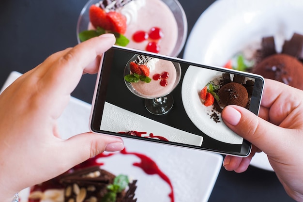 写真 レストランでのスマートフォンによるおいしいデザートの食べ物の写真クリーミーなストロベリースフレとチョコレートフォンダンの写真撮影と新技術がハメ撮り写真をクローズアップ