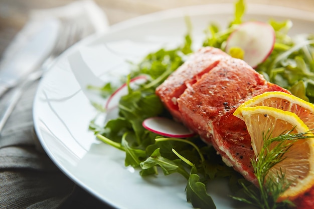 food plate fish protein and salad for health with nutrition lunch and wellness with pescatarian diet salmon rocket leaves and dinner on table with cholesterol for vitamin c benefits and digestion