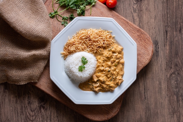 Food plate with chicken stroganoff on wooden table.