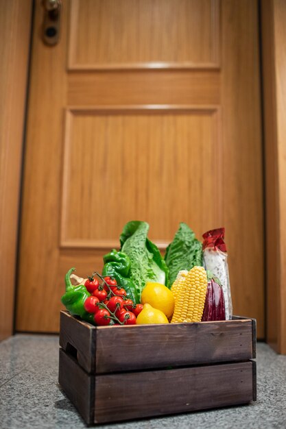 Photo food shopping box stand at the door of the house or apartment vegetables and fruits delivery during quarantine and selfisolation