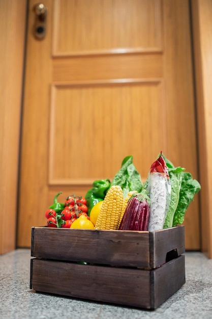 집이나 아파트 문 앞에 식품 쇼핑 상자가 서 있다 검역 및 자가 격리 기간 동안 야채와 과일 배달