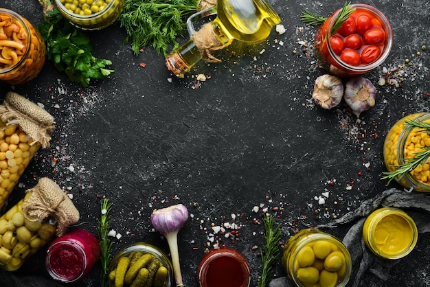 Food stocks in glass jars Pickled vegetables On a black background Top view