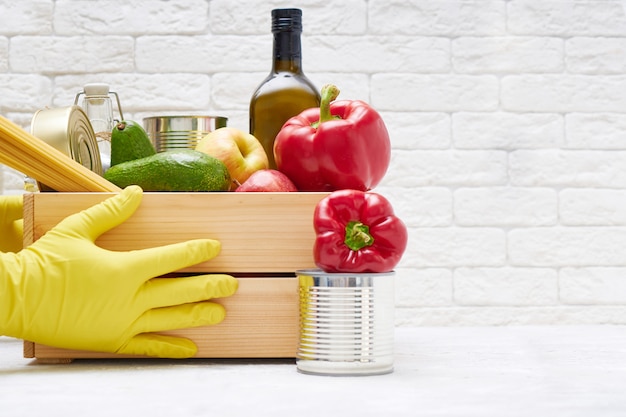 Stock alimentari in una scatola di legno. verdure, olio, frutta, cibo in scatola, pasta. donazione, consegna di cibo, coronavirus