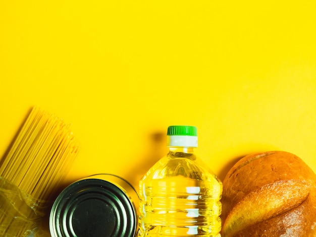 Food supplies crisis food stock isolation on yellow surface. Vermicelli, pasta, canned food, bananas, butter, bread. 