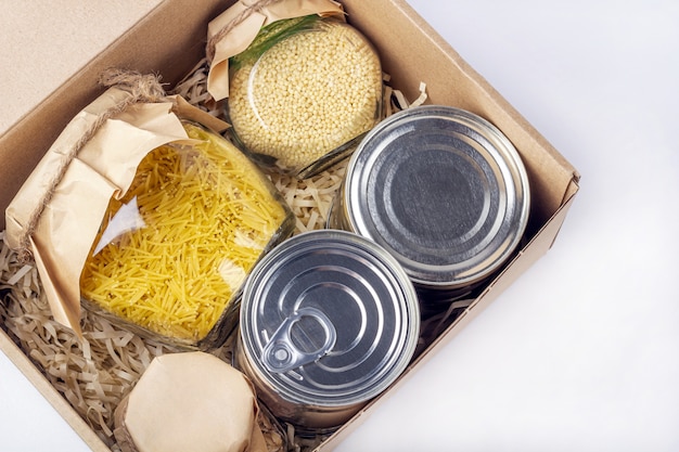 Food supplies during coronavirus quarantine and self-isolation.
food delivery, donation, volunteer support. cardboard box with
various canned food, pasta and cereal.