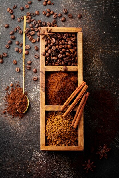 Food surface with three kinds of coffee: beans, milled, instant in wooden box on old concrete brown surface. Rustic stile. Selective focus. Top view.