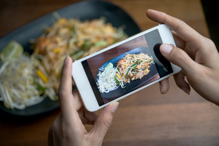 Photo 食品や技術のコンセプト：携帯電話で写真を撮る女性の手