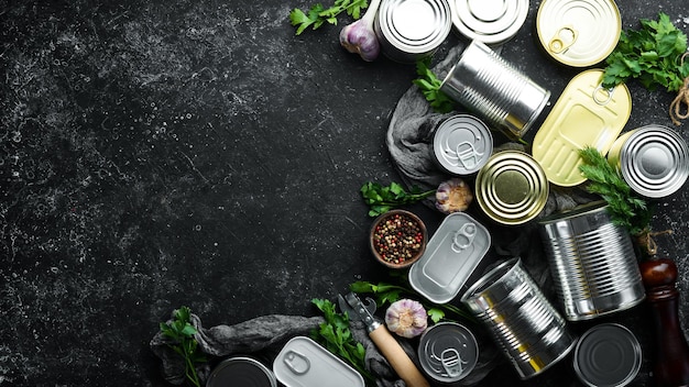 Food in tin cans on black background Food stocks Top view