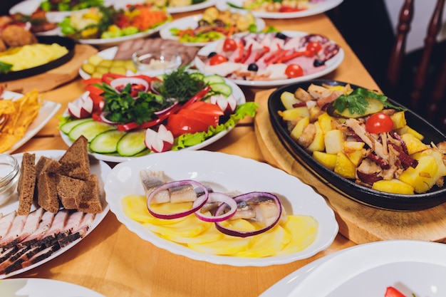 Поднос с вкусной салями, кусочками ветчины, колбасой и салатом. Мясное ассорти с выбором на столе.