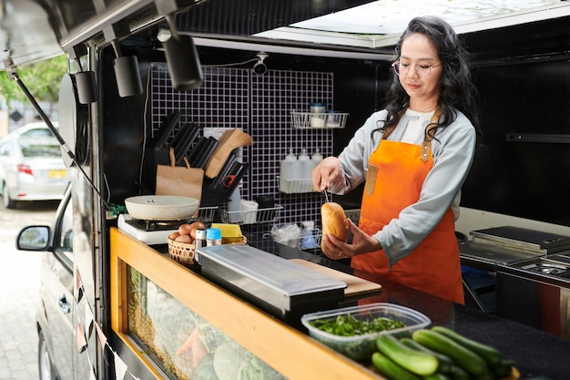 food truck worker cutting bun