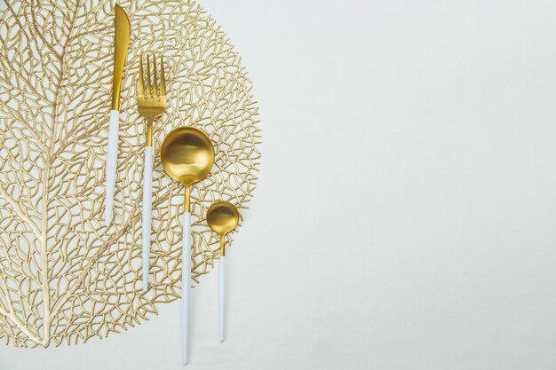 Photo the food utensils gold with a white handle lie on a gold napkin on a white background the concept of