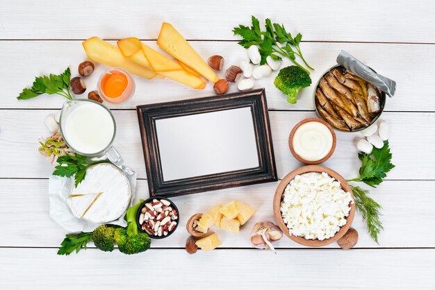 Food with calcium A variety of foods rich in calcium cheese milk parmesan sour cream fish almonds parsley garlic broccoli On a white wooden background Top view Free copy space