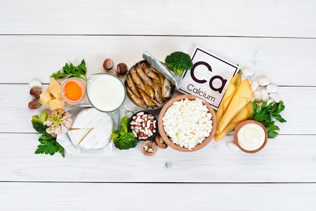 Food with calcium A variety of foods rich in calcium cheese milk parmesan sour cream fish almonds parsley garlic broccoli On a white wooden background Top view Free copy space