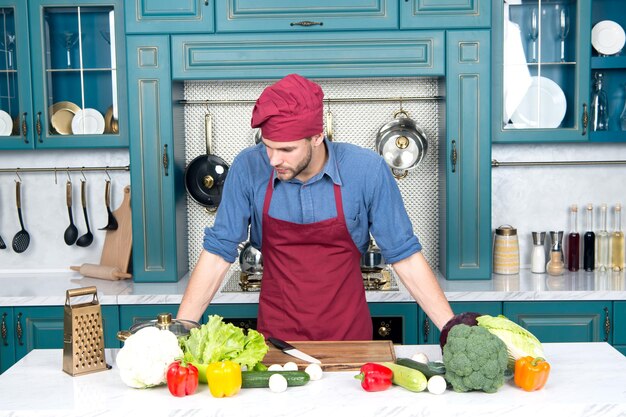 식탁에 건강한 비타민이 있는 음식과 주방에서 요리사 모자를 쓴 남자 음식 준비 및 요리법