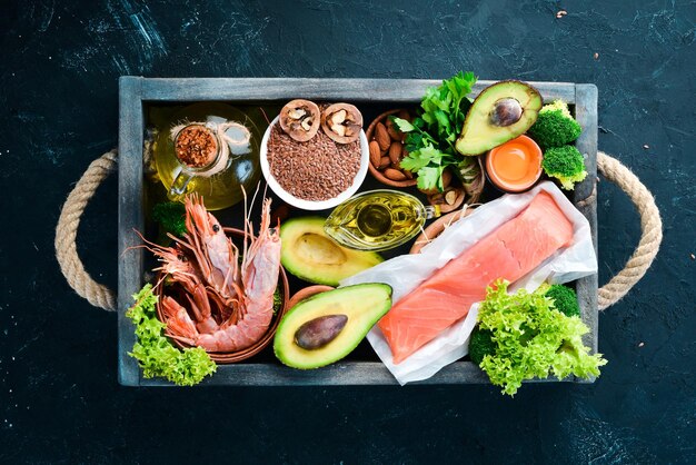 天然ビタミンを含む食品オメガ3健康食品魚エビブロッコリー亜麻ナッツ卵パセリ上面図テキスト用の空きスペース黒い背景に
