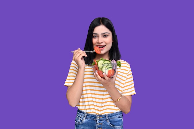 Foodie girl eating tomato from vegitable bowl indian pakistani model