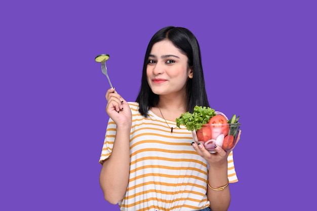 サラダのボウルとスプーンでキュウリのスライスを保持している食通の女の子インドのパキスタンモデル