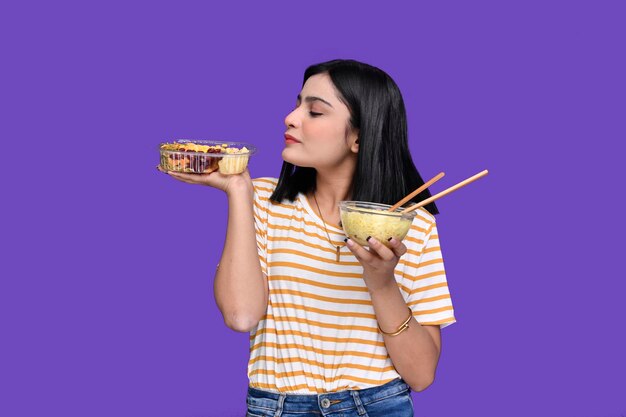 Foodie girl holding spaghetti and noodles posing over purple background indain pakistani model