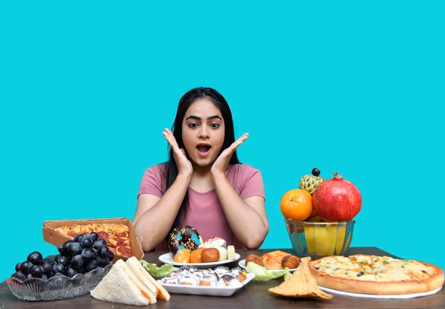 Photo foodie girl sitting at fruit table shocking hands on table looking front indian pakistani model