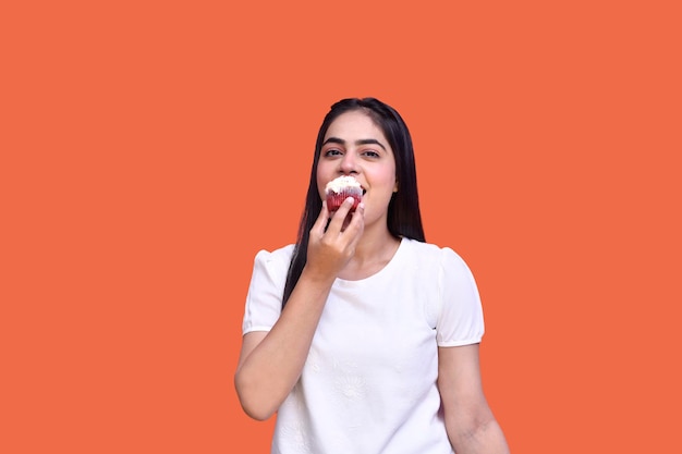 foodie girl wearing t-shirt and eating cupcake indian pakistani model