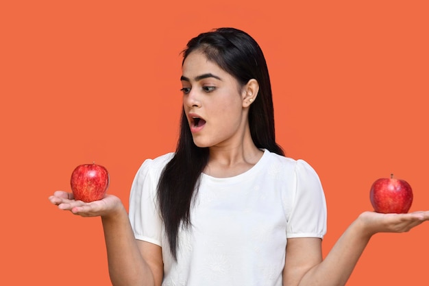 foodie girl wearing white tshirt holding two apples hands with opened mouth indian pakistan model