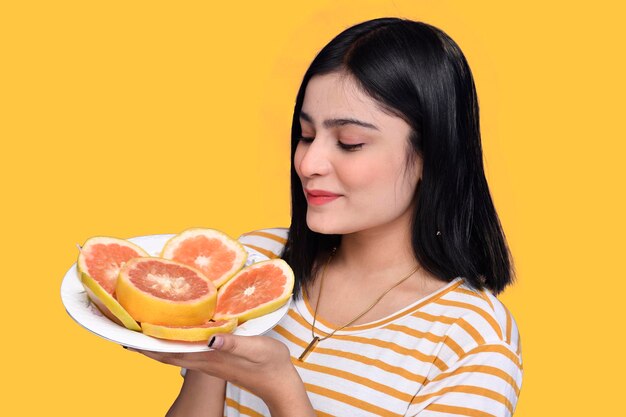 foodie meisje houdt een bord met citrusvruchten vast en kijkt naar het Indiase Pakistaanse model