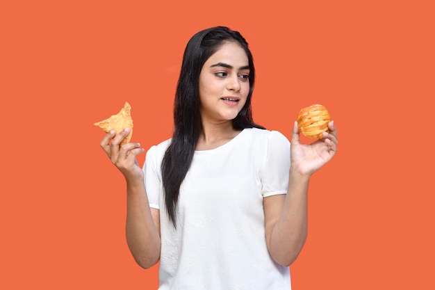 foodie-meisje met een wit t-shirt glimlachend en dount en pasteitjes op ogen indiaans pakistaans model