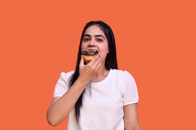 foodie meisje met witte t-shirt die chocoladetaart eet en naar voren kijkt indiaans pakistaans model