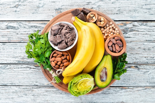 Foods containing natural magnesium Mg Chocolate banana cocoa nuts avocados broccoli almonds Top view On a white wooden background