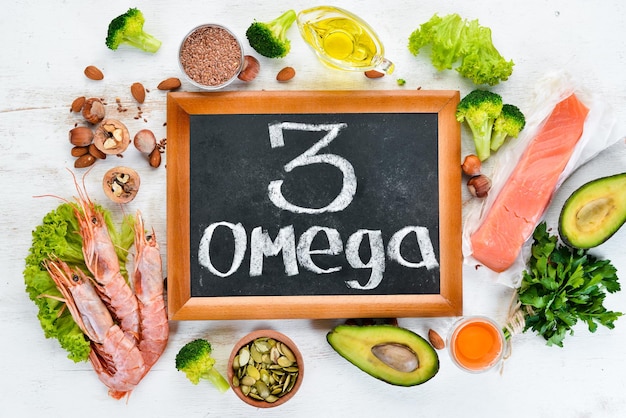 オメガ3を含む食品。ビタミン健康食品：アボカド、魚、エビ、ブロッコリー、亜麻、ナッツ、卵、パセリ。上面図。テキスト用の空き容量。白い木製の背景に。