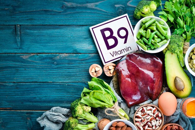 Foods that contain natural vitamin B9 Liver avocado broccoli spinach parsley beans nuts on a blue background Top view