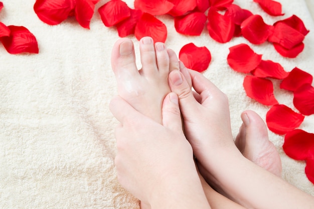 Foot care. Beautiful female legs and rose petals