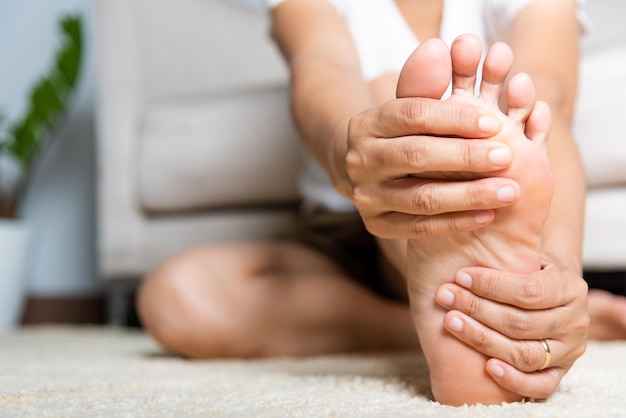 Foto dolore al piede donna asiatica che sente dolore al piede a casa