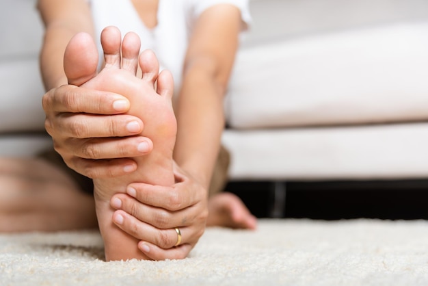 Photo foot pain woman feeling pain in her foot at home female suffering from feet ache use hand massage