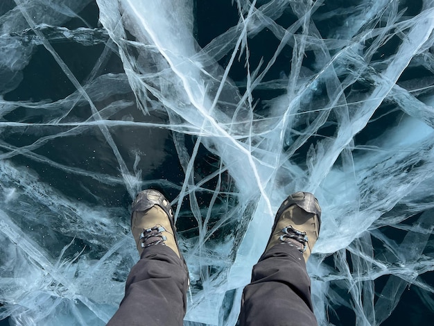 A foot of tourist standing on the cracks surface of frozen lake Baikal in the winter season of Siberia Russia