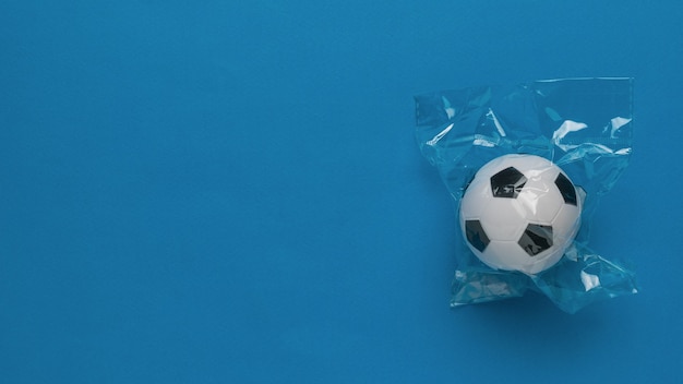 Un pallone da calcio in una confezione di cellophan su sfondo blu. posto per il testo.