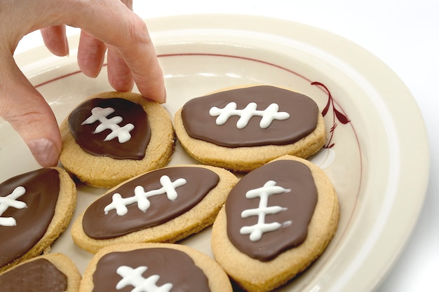 Football cookies on plate hand taking cookie from plate