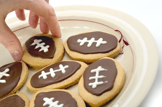 Biscotti di calcio sulla mano del piatto che prende il biscotto dal piatto