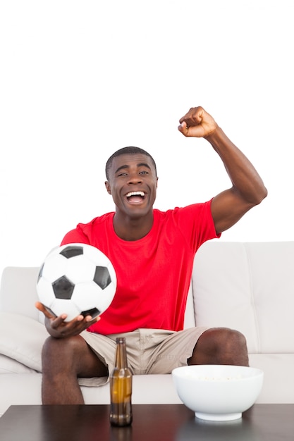 Premium Photo Football fan in red jersey sitting on couch cheering